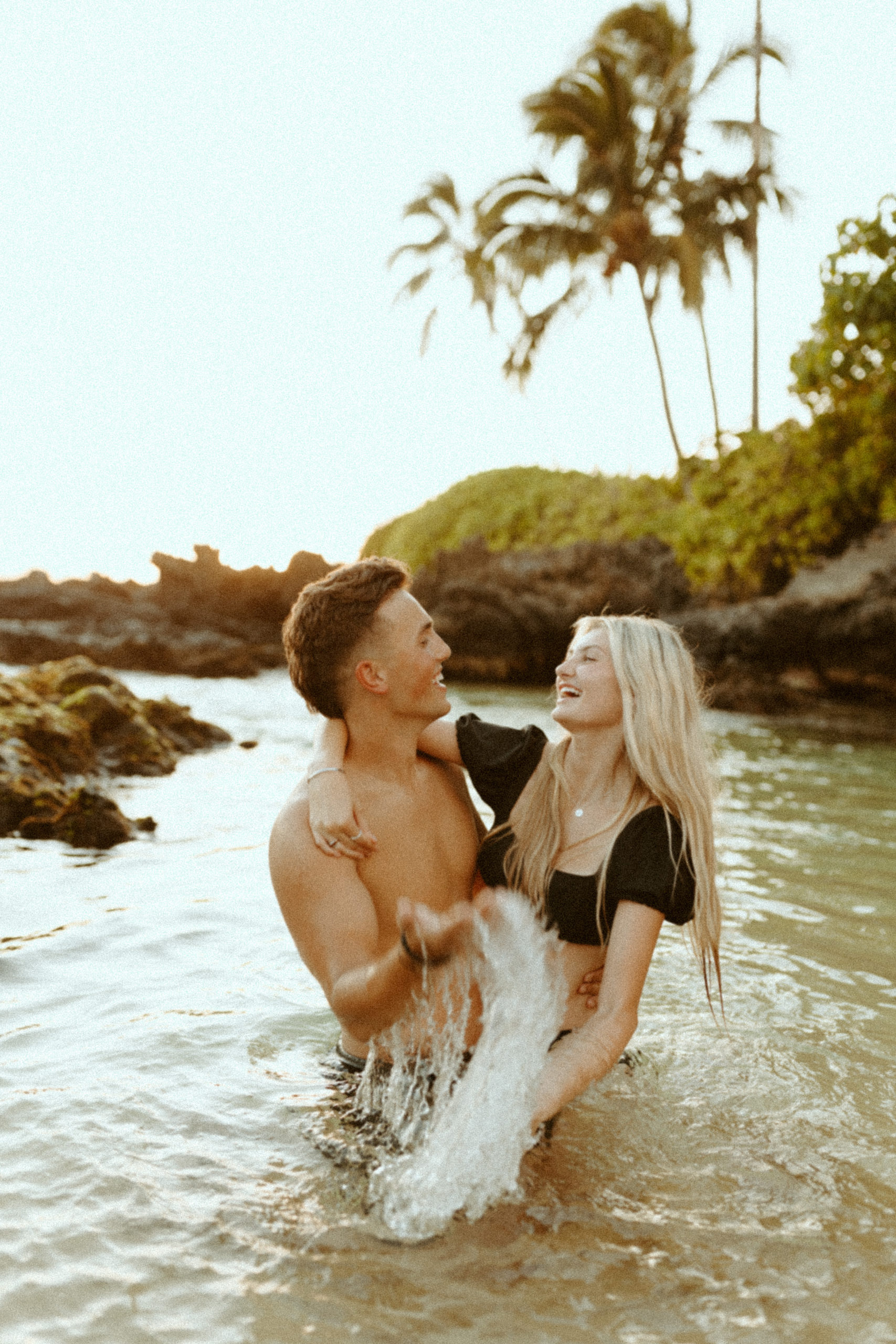 couple smiling as they play together in the ocean