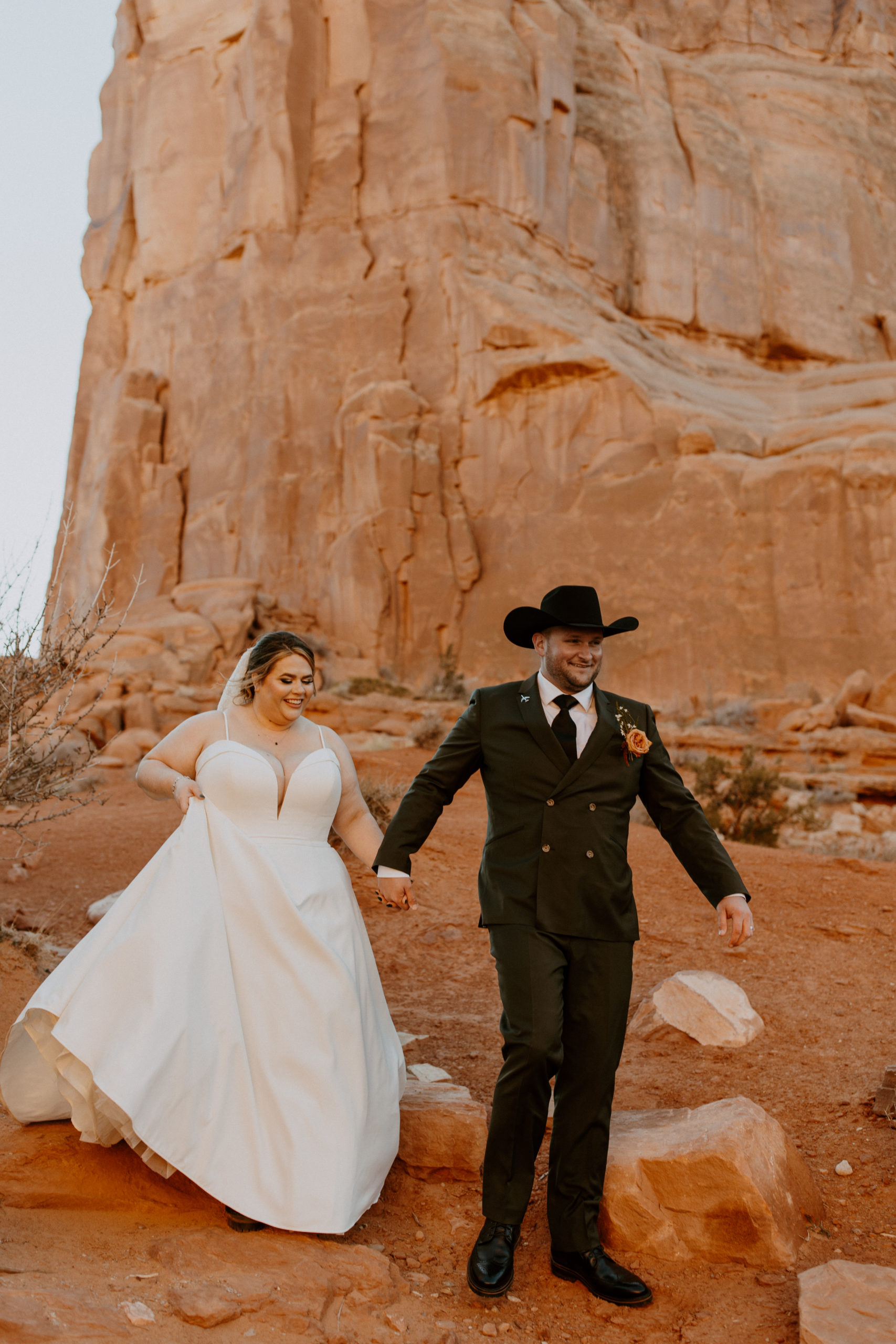 the couple walking down the rocks at Arches National Park in Utah