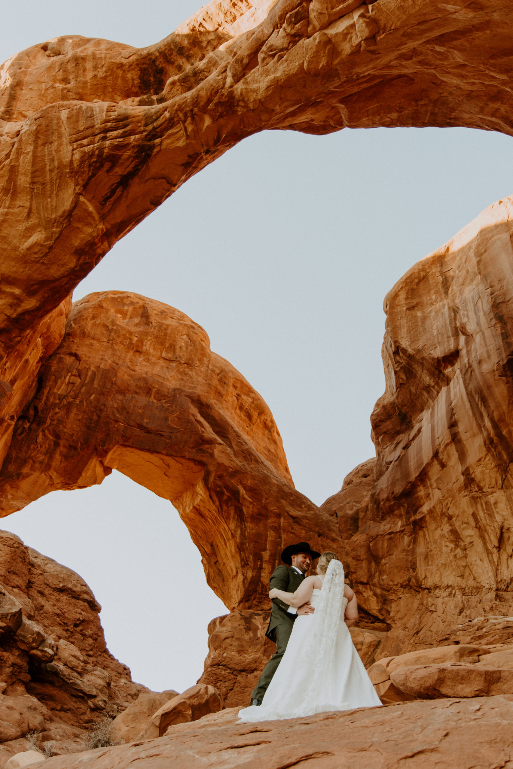 the couple standing under the arches at Arches National Park