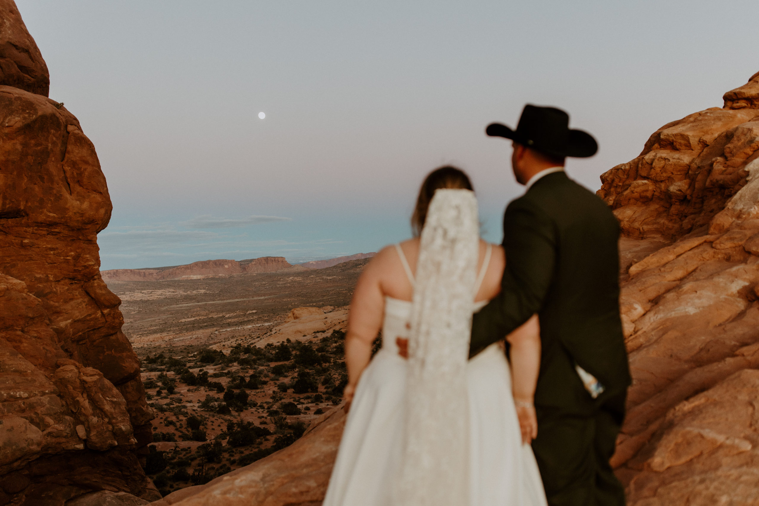 the couple looking at the moon together at Arches National Park in Utah