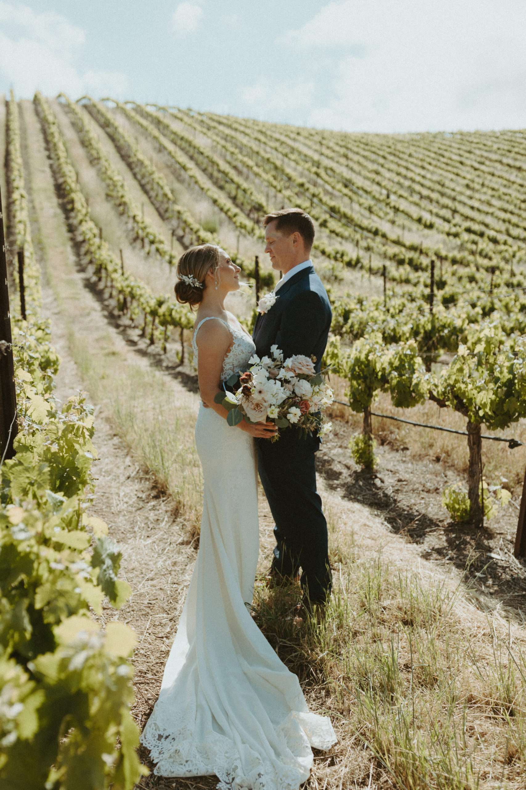the bride and groom looking at each other in the vineyard