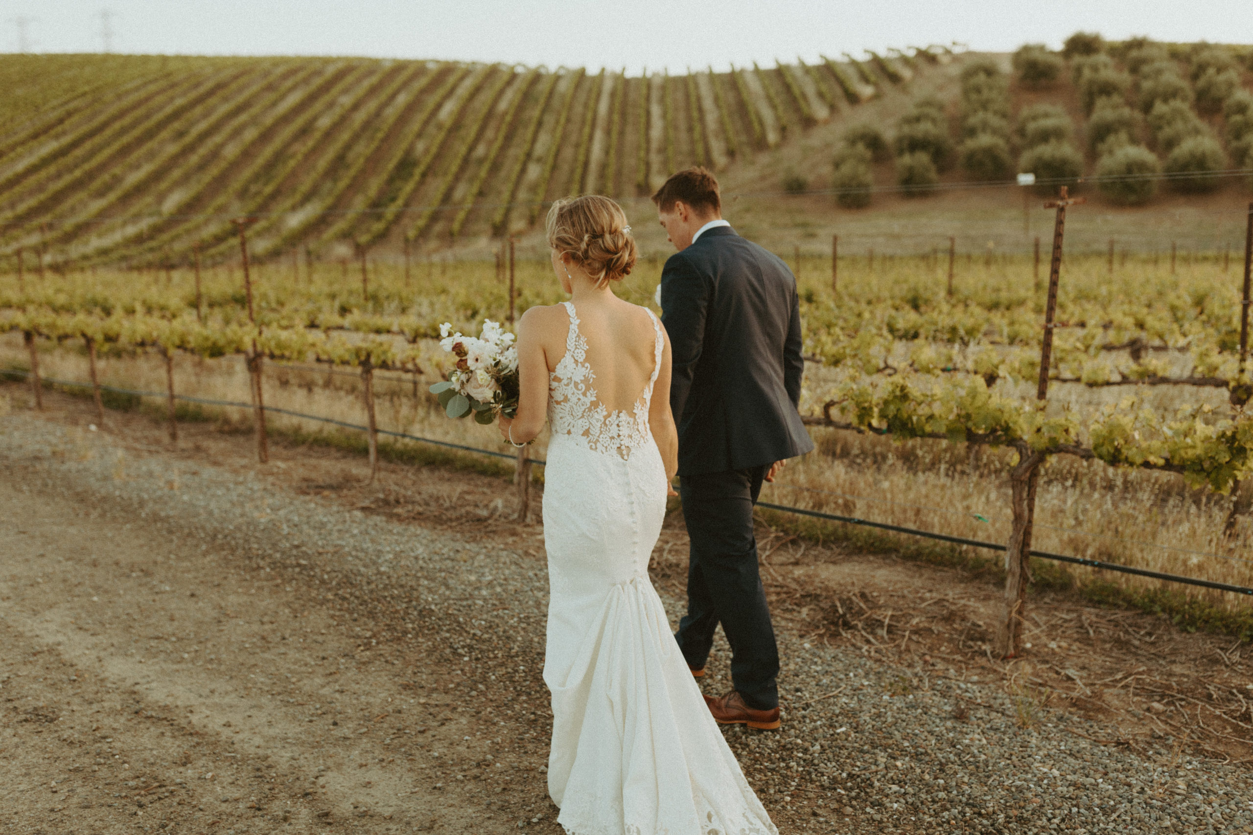 the couple walking along the side of the vineyard in California
