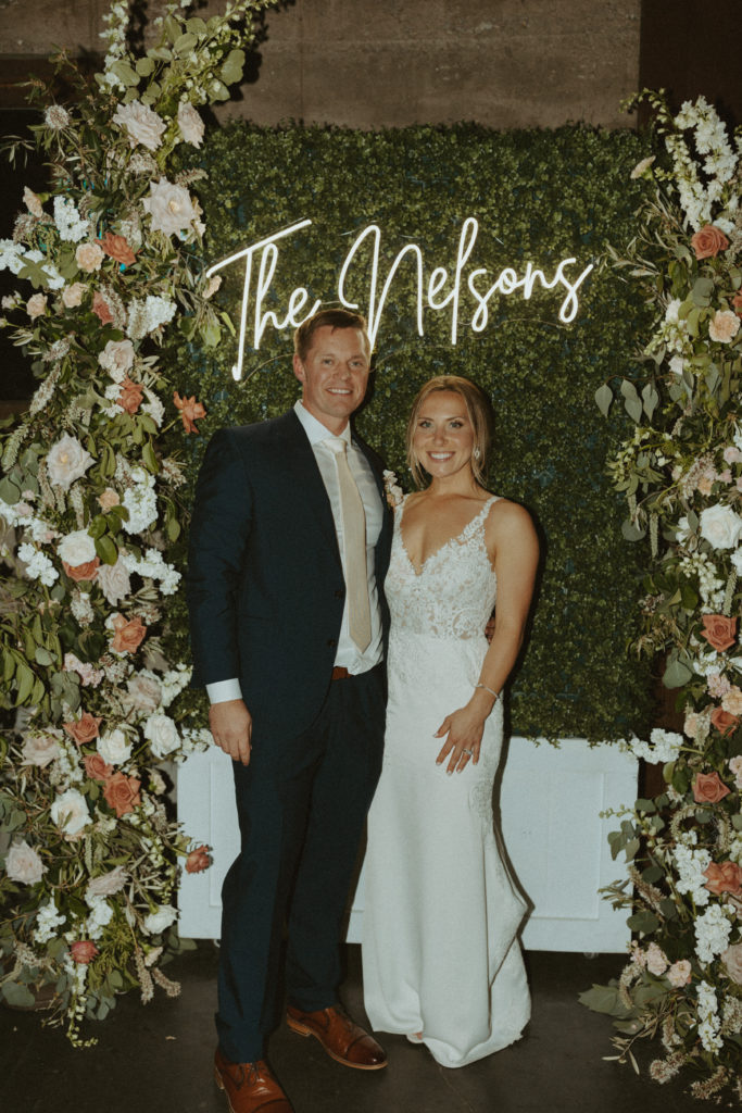 the couple smiling by the reception sign