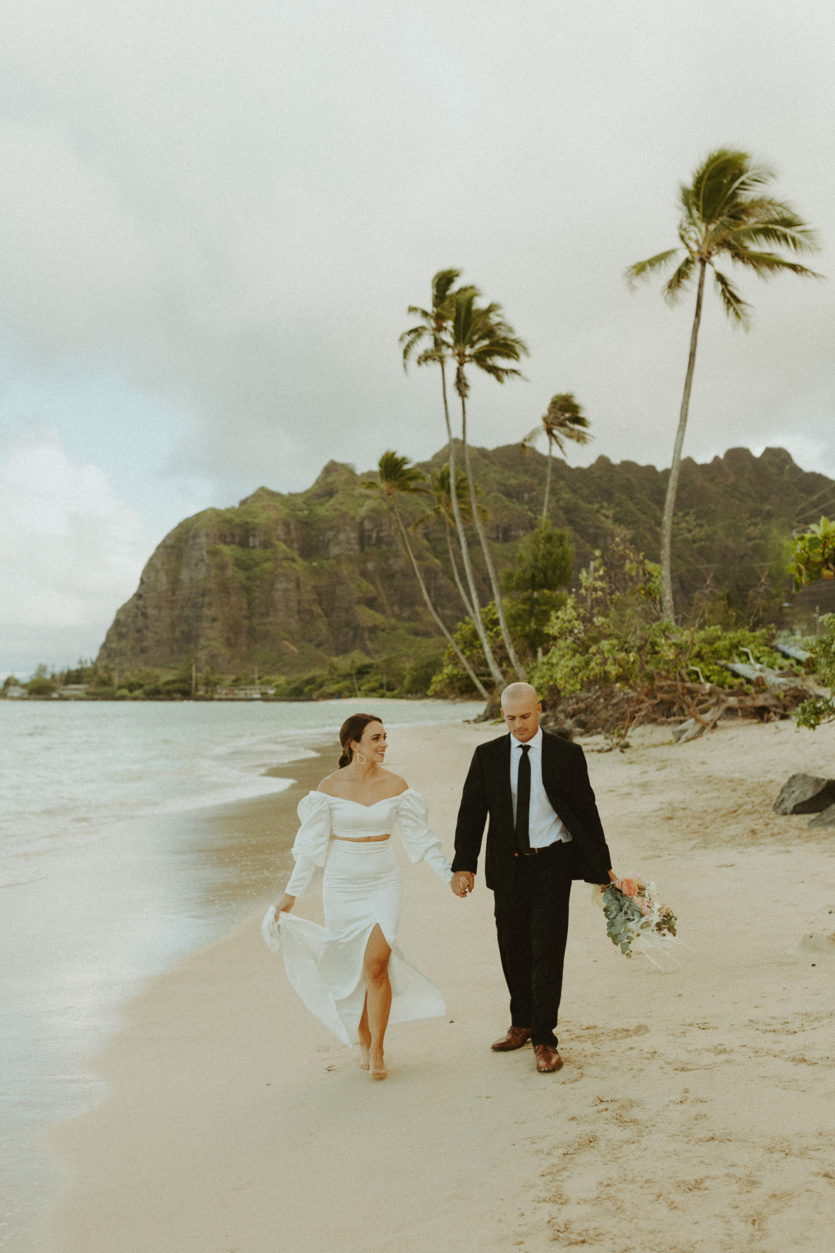 the couple walking down the beach at Kualoa Ranch in Oahu