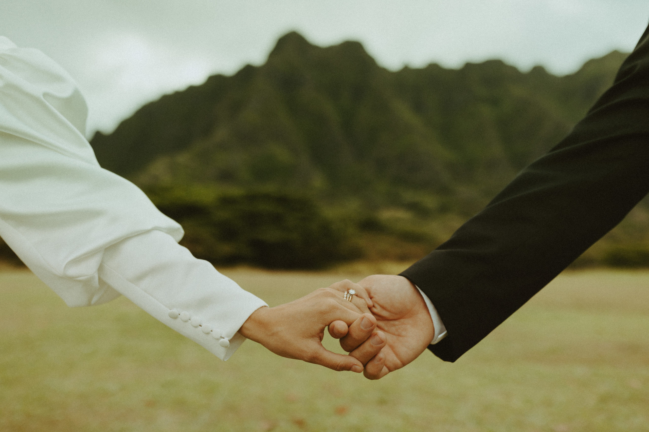 the hands of the couple in front of the mountain
