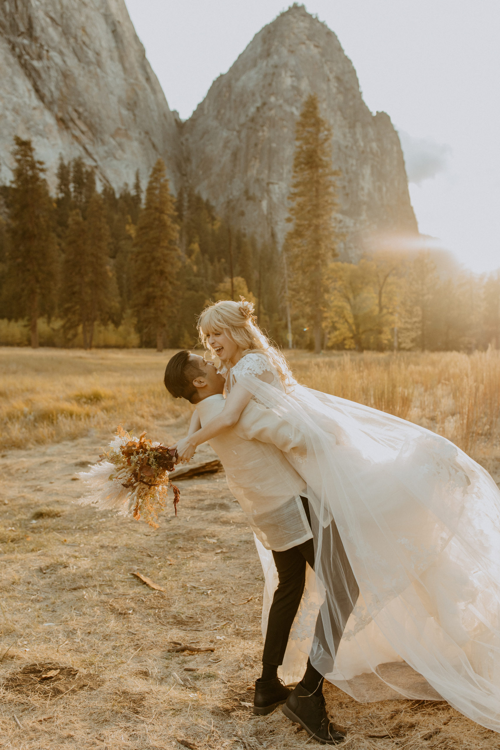 the bride laughing as the groom picks her up at the elopement in Yosemite
