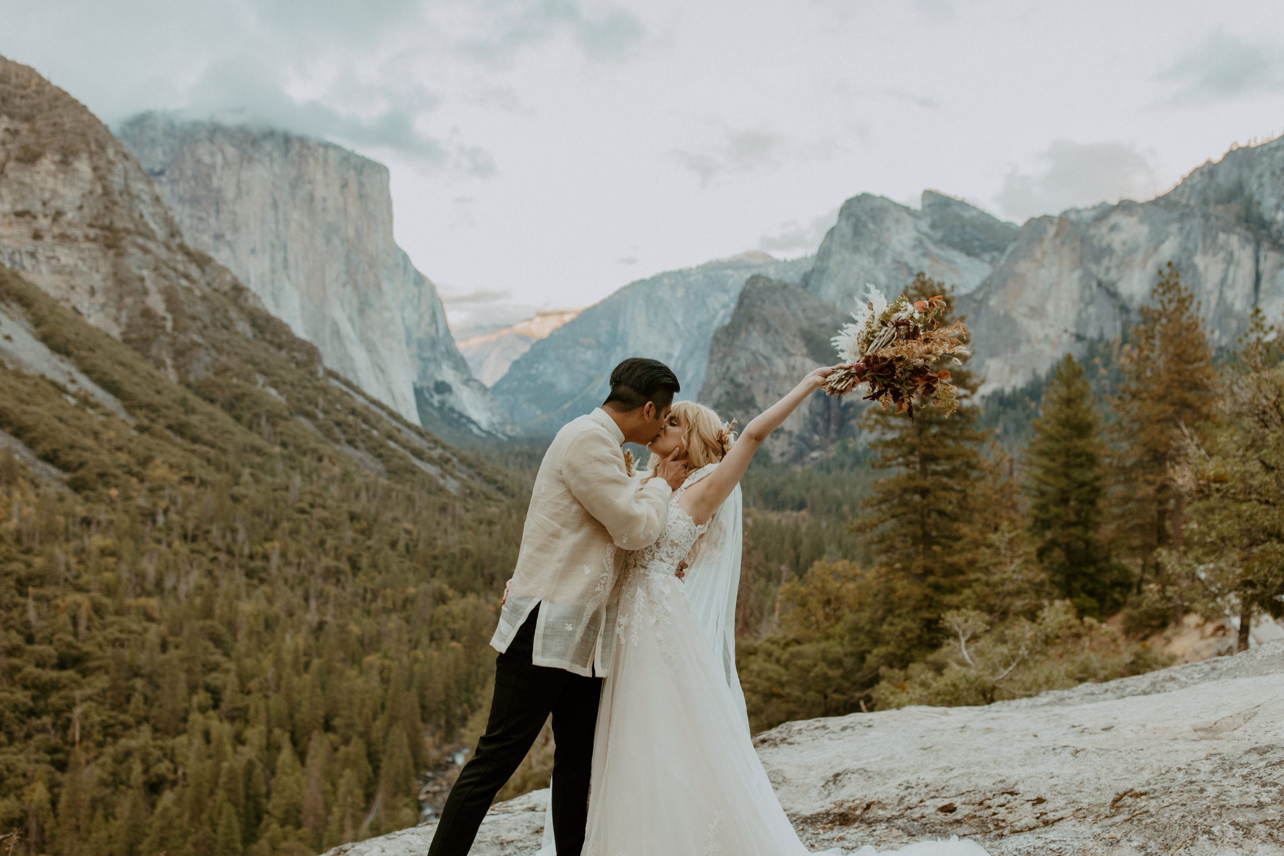 the bride raising her bouquet in the air at Tunnel View in Yosemite
