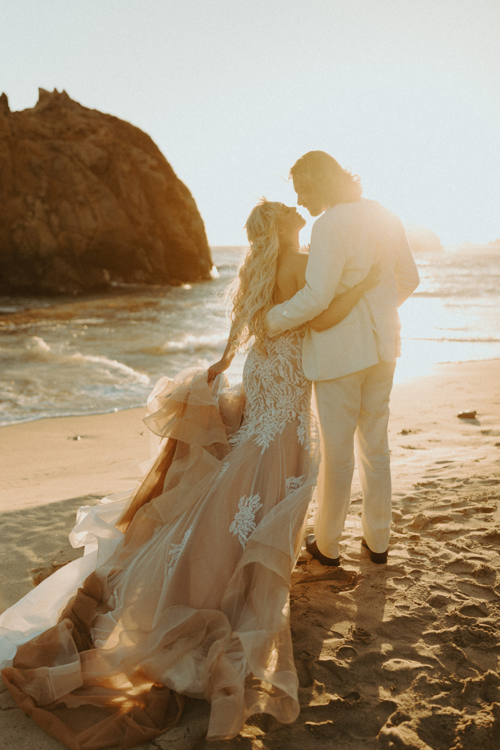 the couple standing by the water looking at each other at their Big Sur wedding