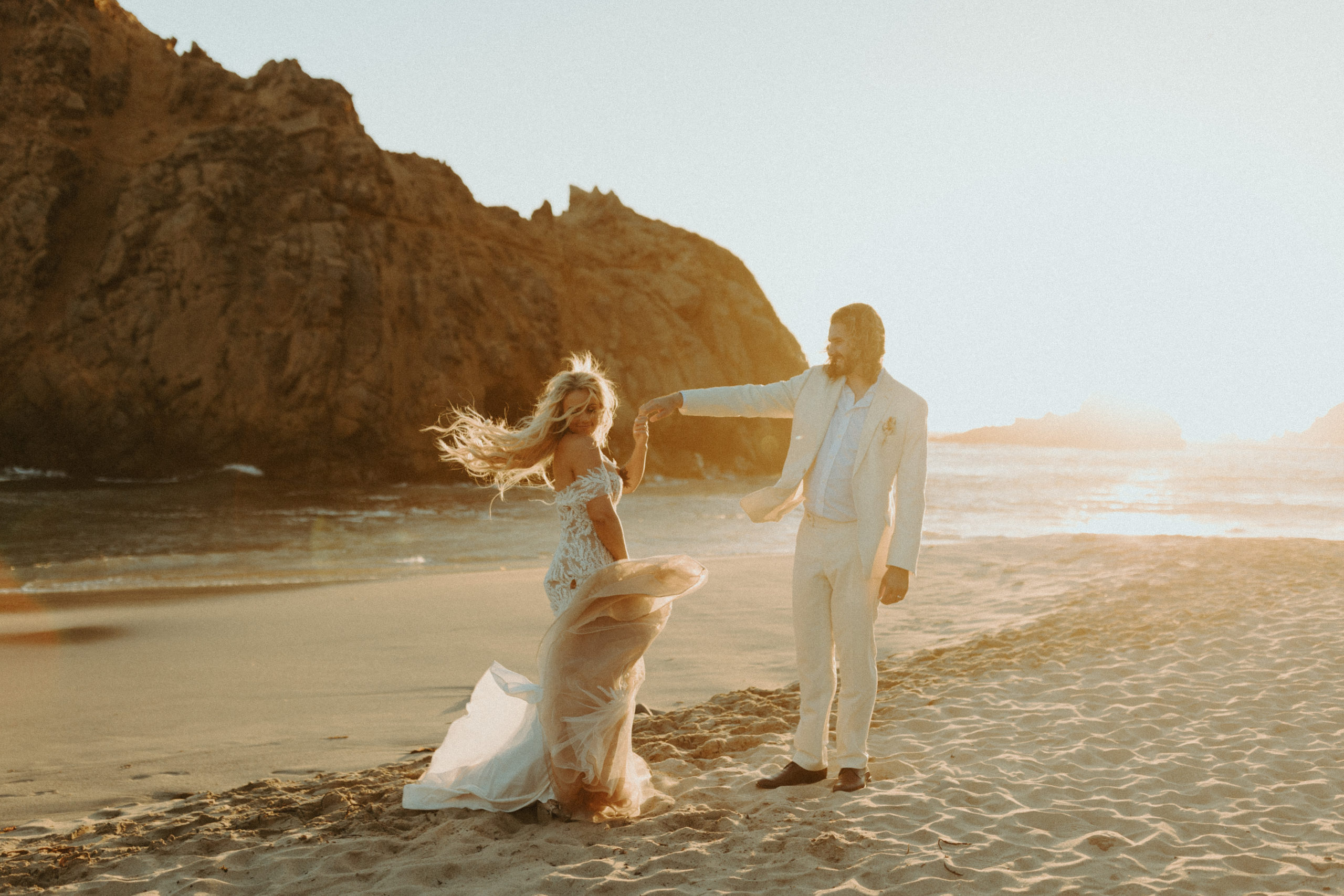 the couple twirling and dancing on the beach at their Big Sur Wedding