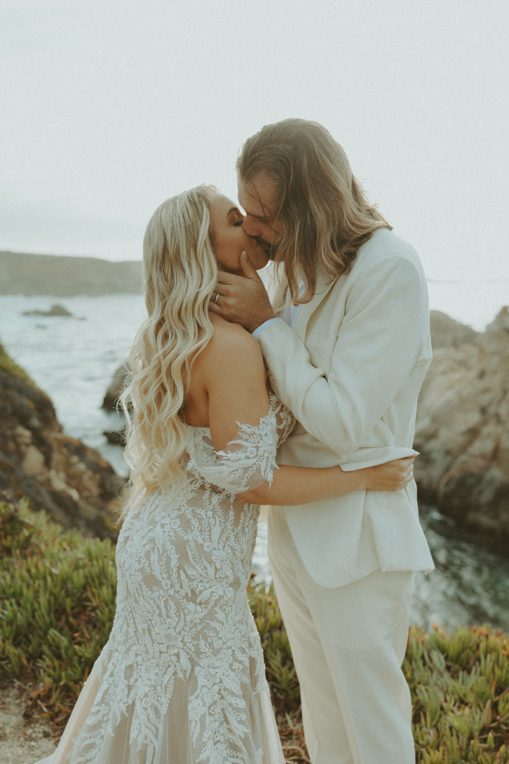 the bride and groom kissing on the cliffs of Big Sur