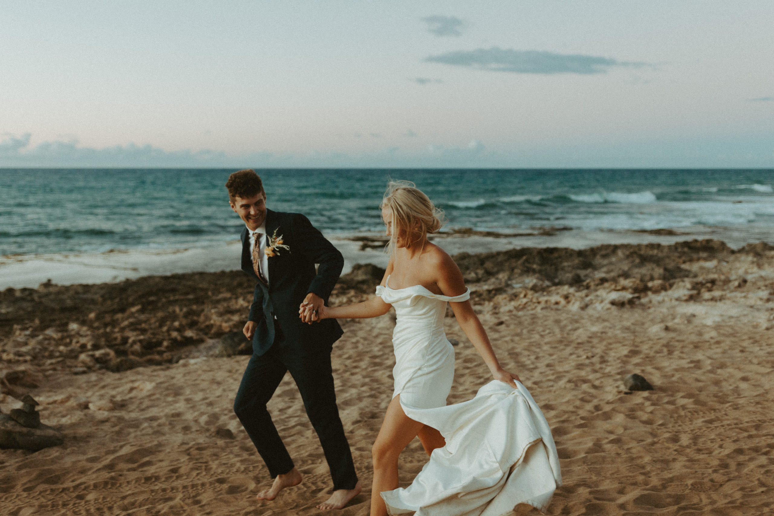 the bridal couple running down the beach after their Hawaii elopement