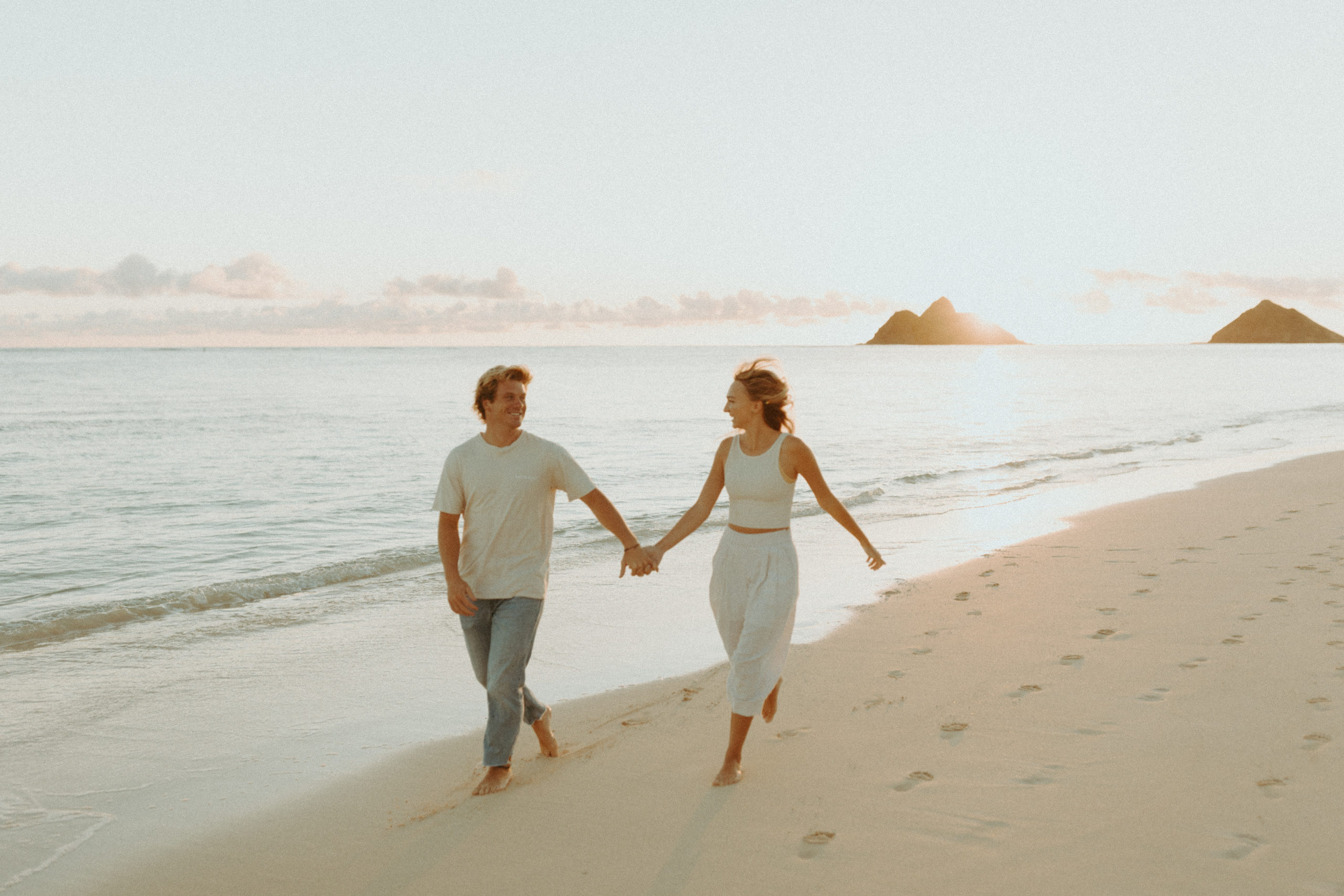 the couple holding hands as they run along the beach together