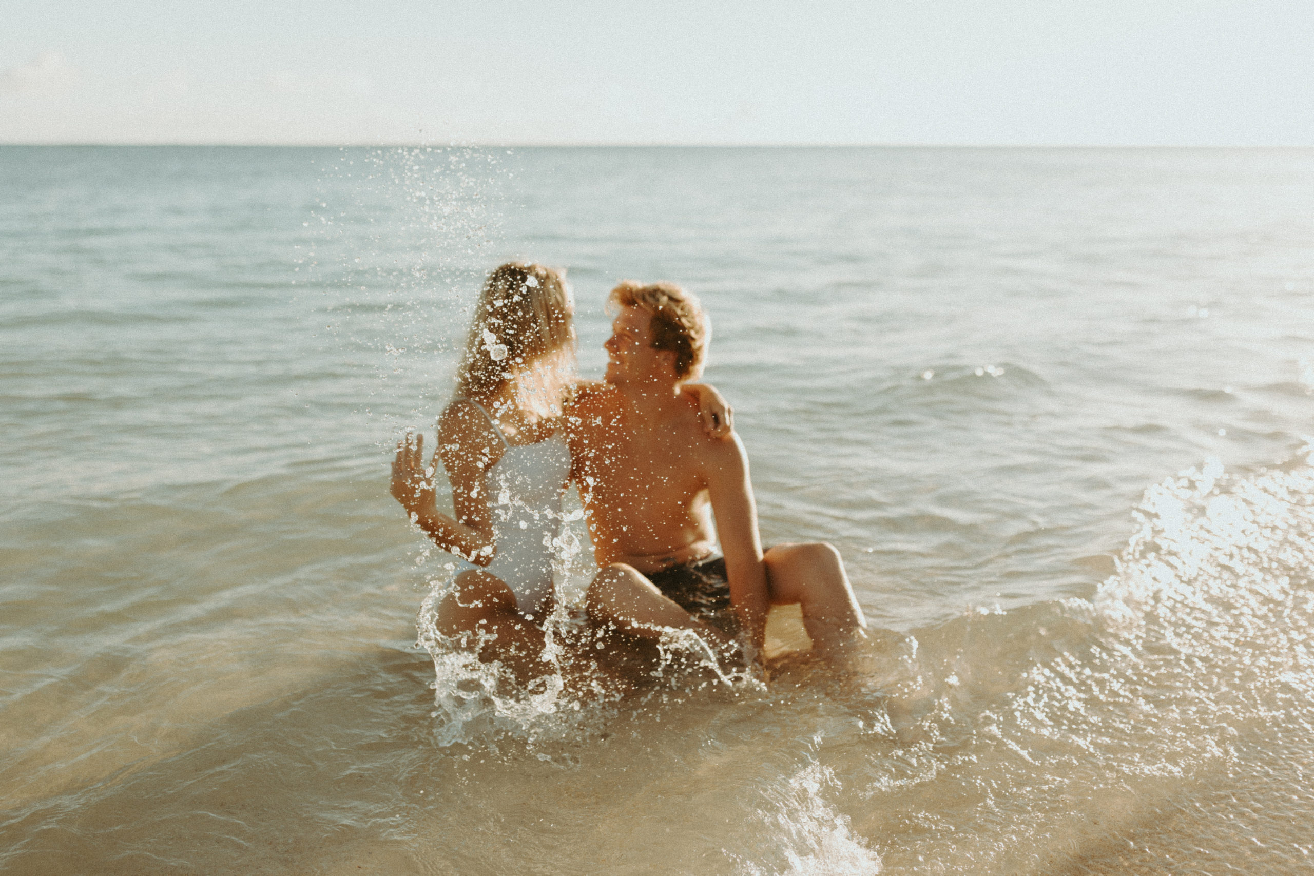 the couple splashing in the ocean as a sunrise photoshoot couple idea