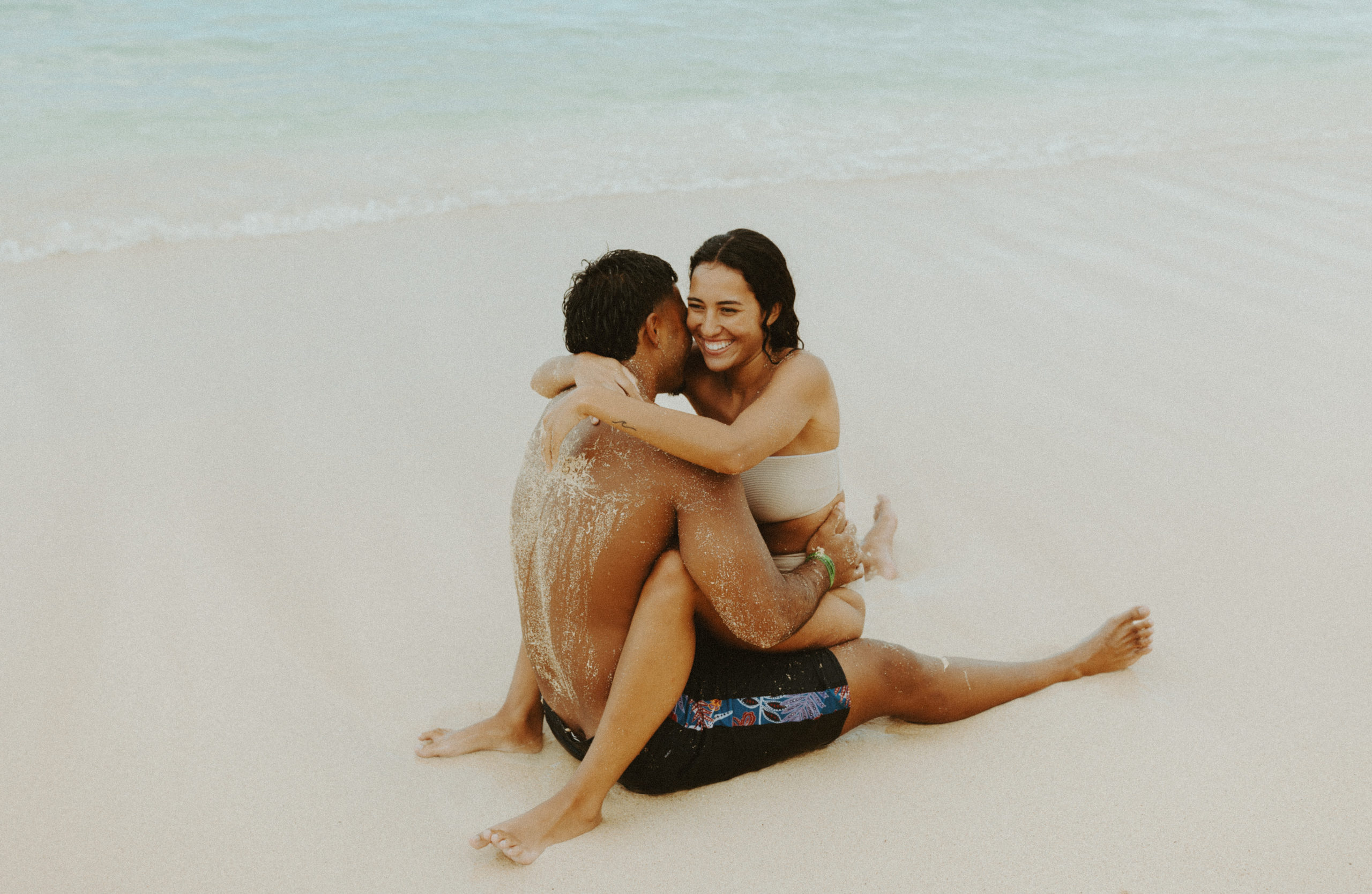 the couple laughing and hugging in the sand