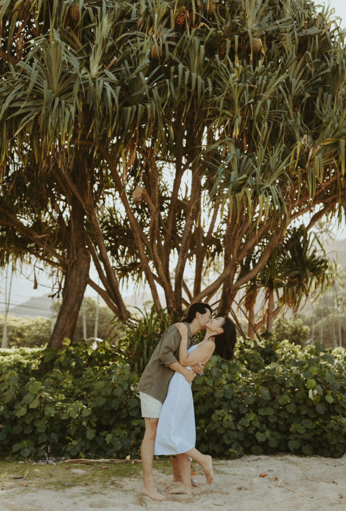the couple underneath trees in Hawaii for their engagement pictures