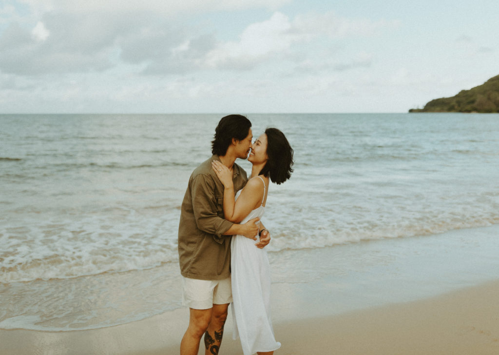 the engaged couple kissing on the beach in Hawaii during their engagement session