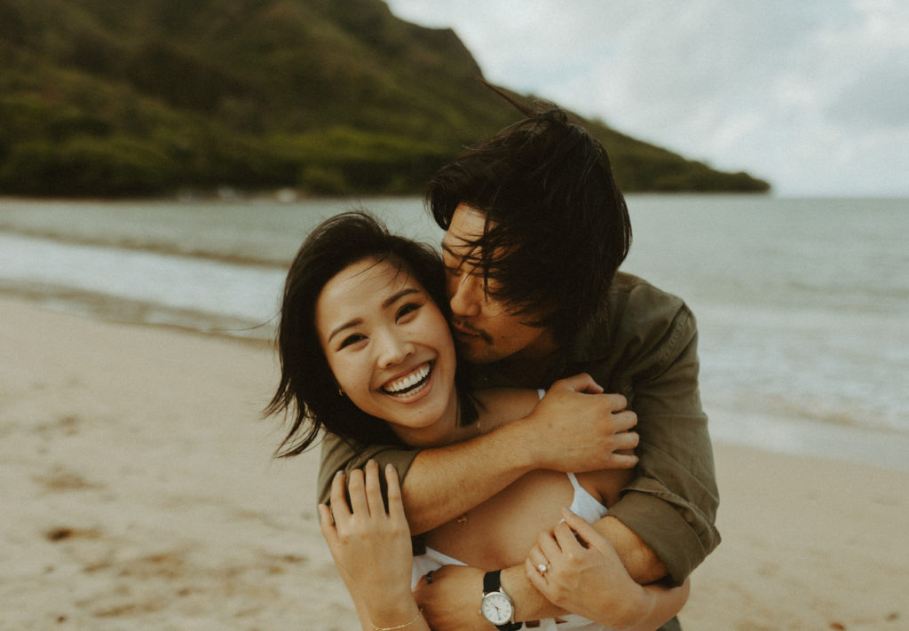the couple smiling together on the beach during their engagement photos