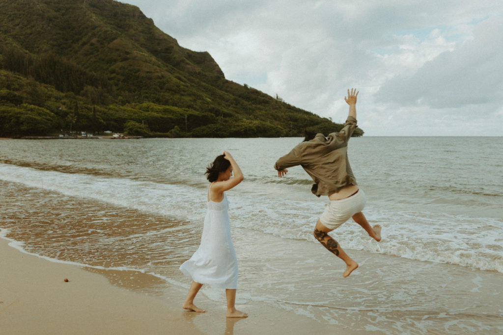 the couple being silly and jumping in the water during their engagement photos