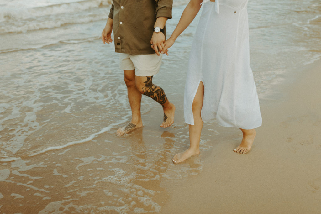 the couple's legs as they walk down the beach for engagement photos in Hawaii