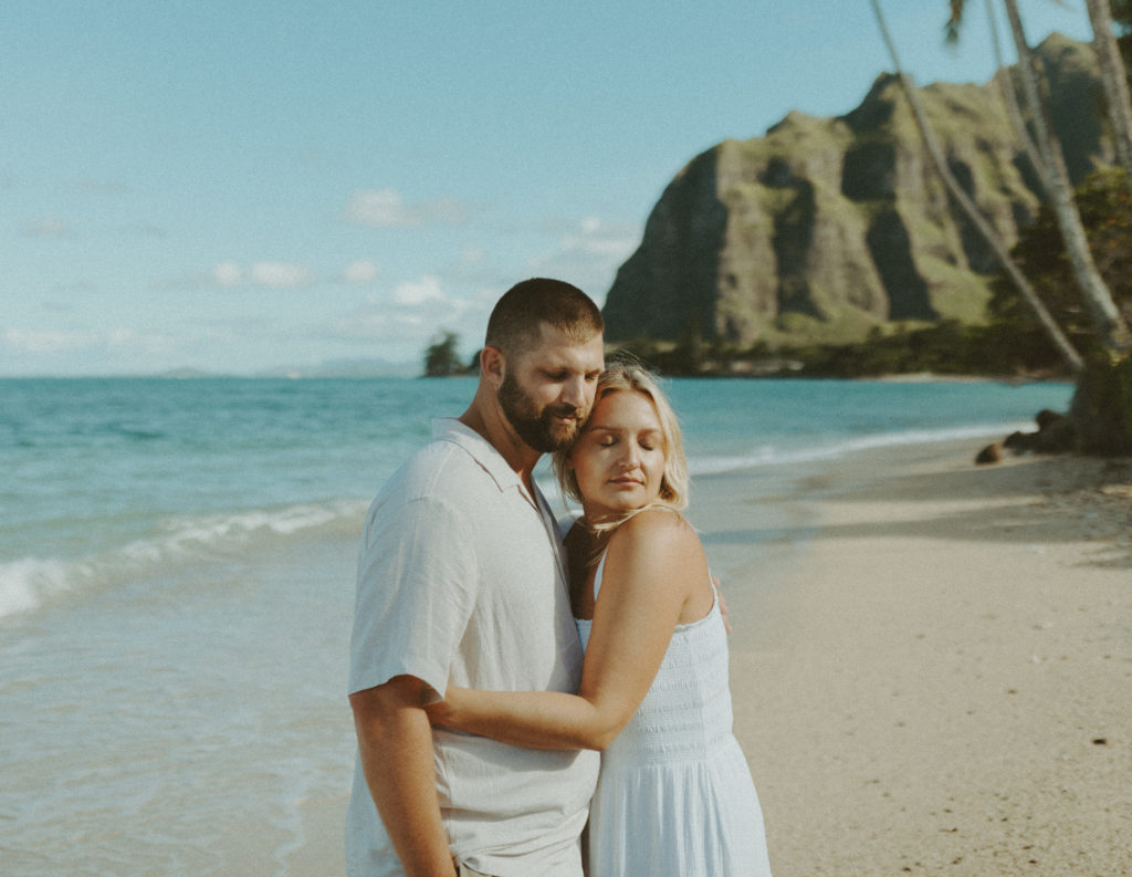 the couple hugging in Hawaii on the beach during their beach couples photoshoot for their anniversary
