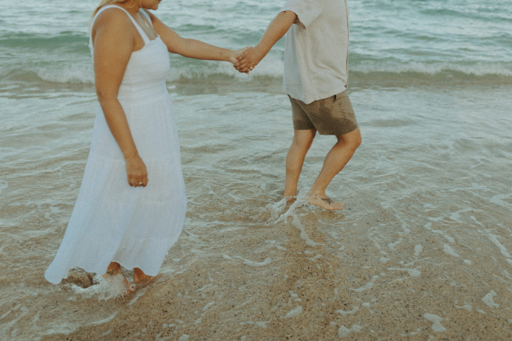 the couple wading in the water as they hold hands