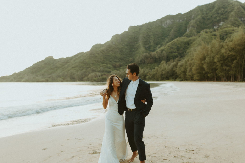 the bridal couple walking along the beach together in their elopement dress and suit
