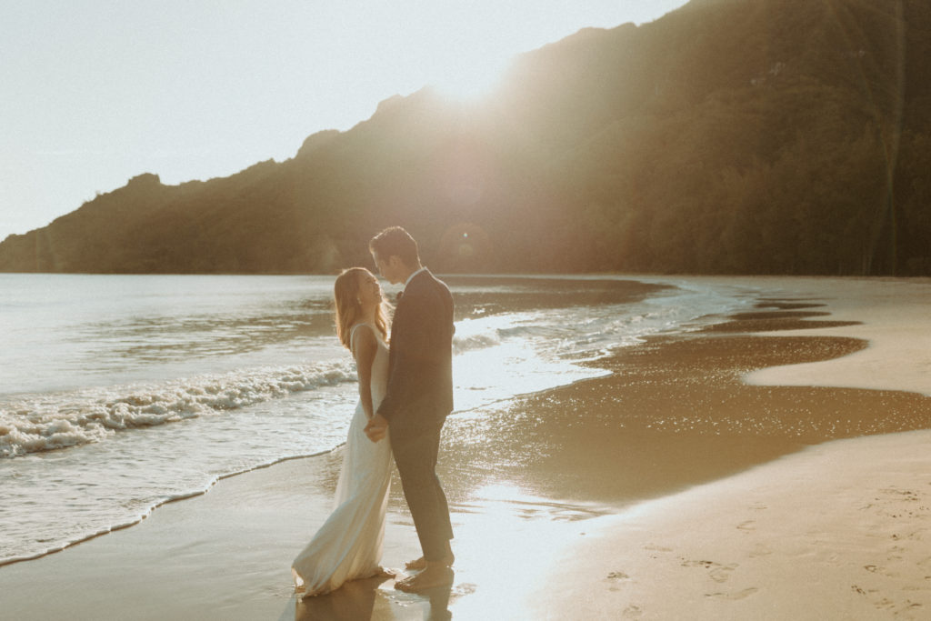 the couple standing together on the beach in Hawaii 