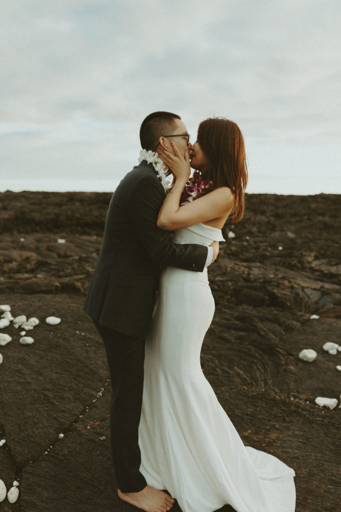 the wedding couple kissing on the lava rock during their Hawaii wedding photos