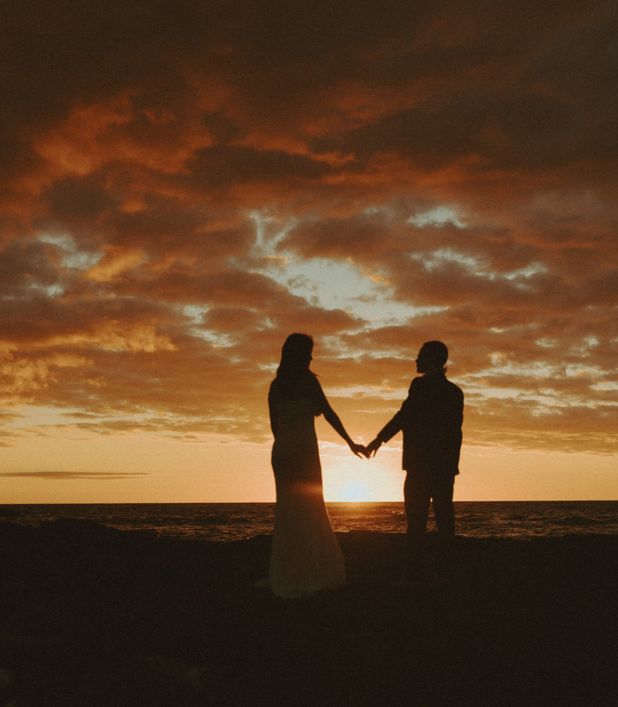 the couple holding hands for sunset pictures in Hawaii