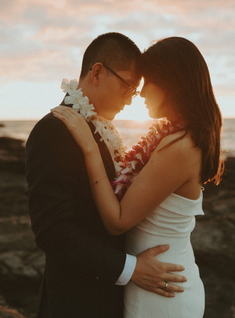 the wedding couple touching foreheads as for sunset pictures during their Hawaii wedding