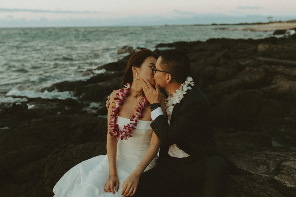 the bride and groom kissing on the lava rock during their Hawaii wedding for wedding photos