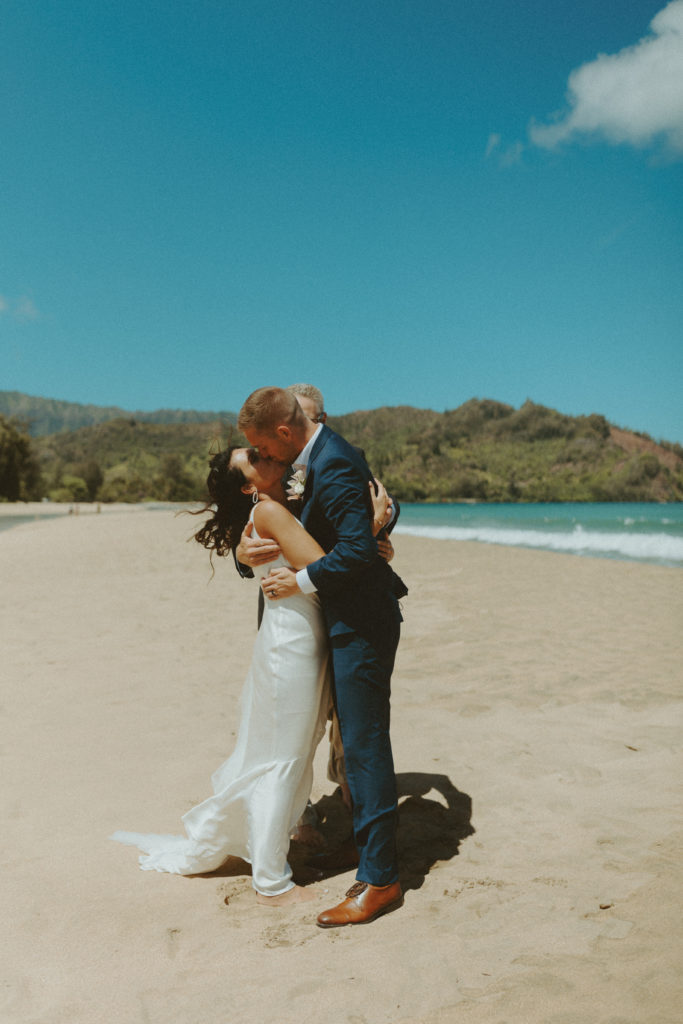 the bride and groom's first kiss on the beach during their elopement ceremony on the beach in Kauai