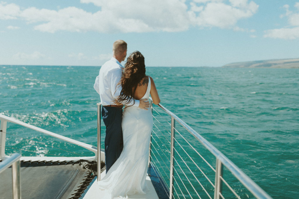 the couple standing on the boat and looking out at the ocean