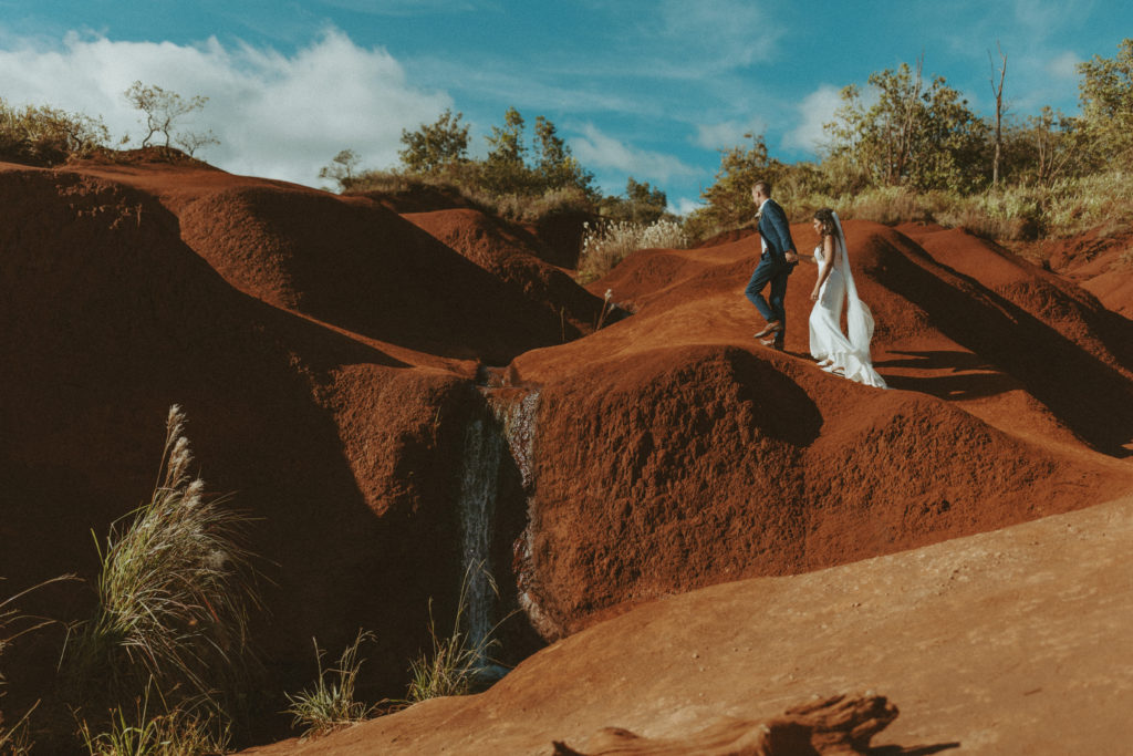 the couple climbing on the rocks in Hawaii during their adventure elopement