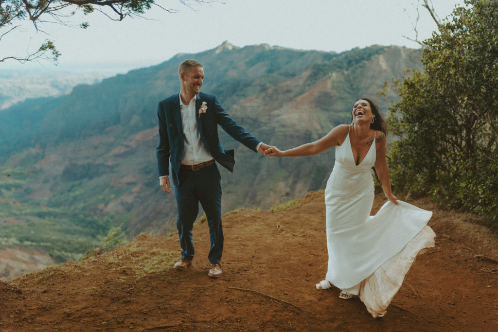 the couple holding hands and laughing with one another during their elopement in Hawaii