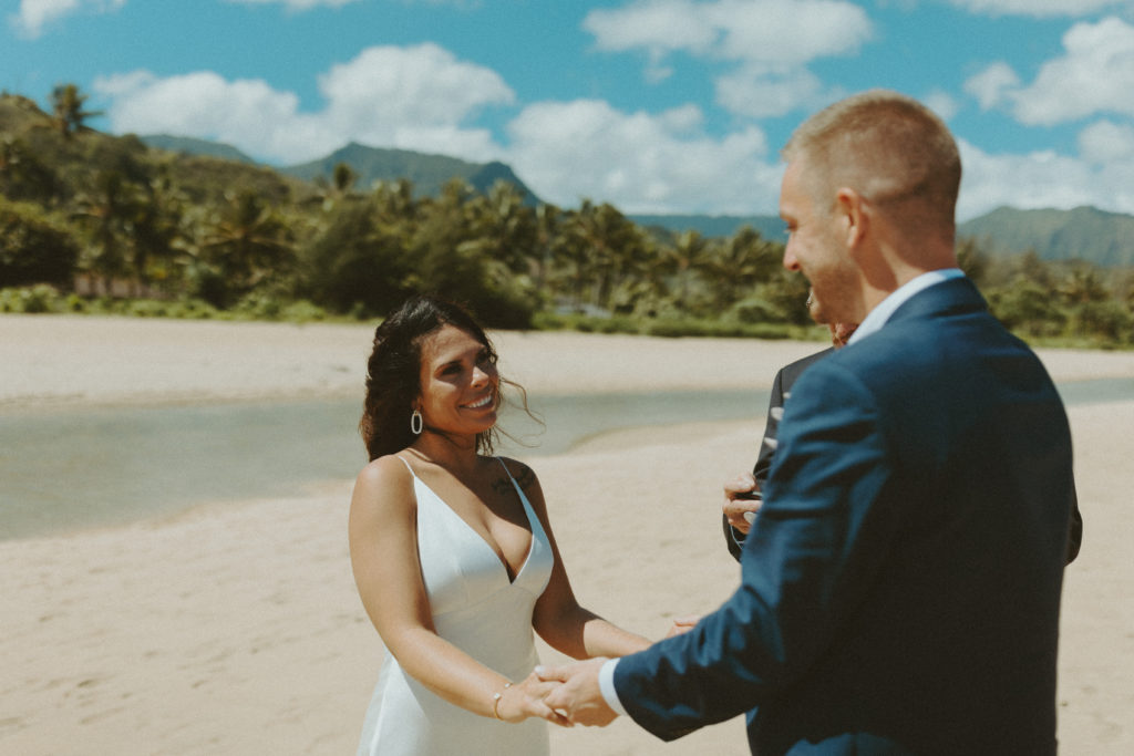 the wedding couple holding hands at their beach wedding ceremony in Kauai Hawaii