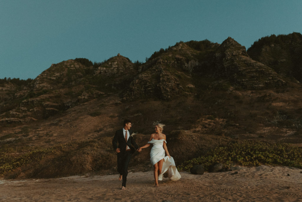 the couple running towards the Hawaii elopement photographer for wedding photos in Oahu