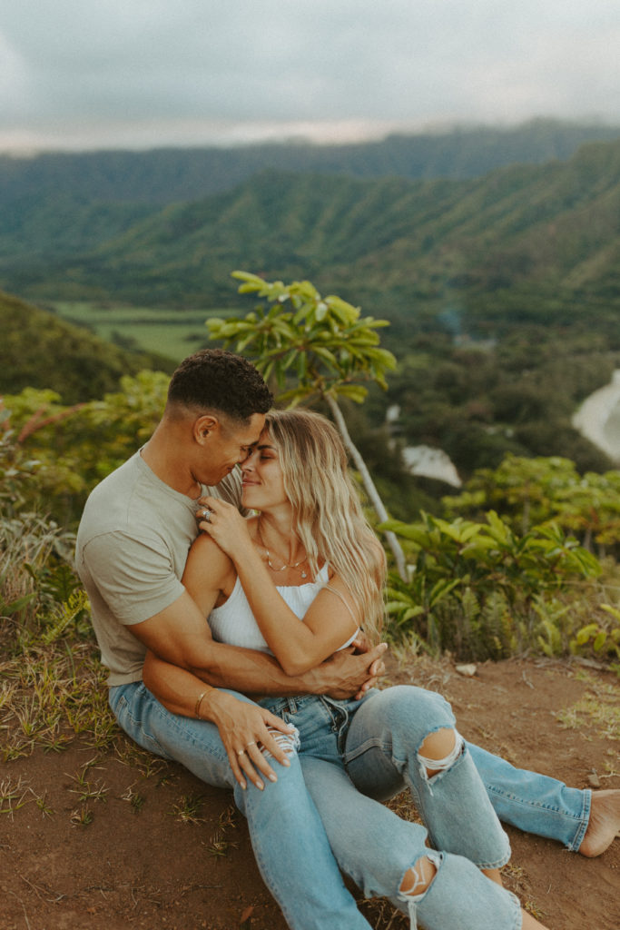 the couple sitting on the ground for an adventure couples photoshoot in Hawaii