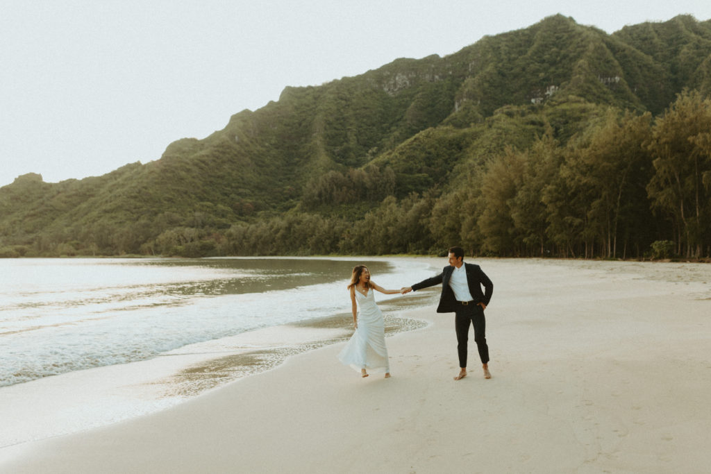 the couple holding hands as they walk on the beach for beach pictures for elopement photos