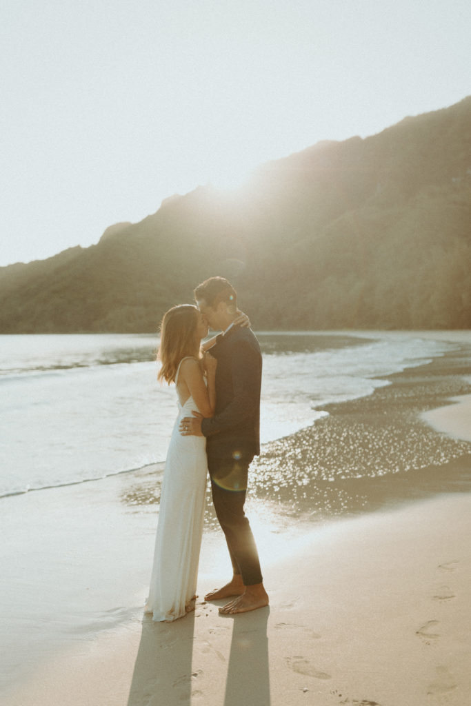 the elopement couple kissing in the sunlight on beach in Hawaii