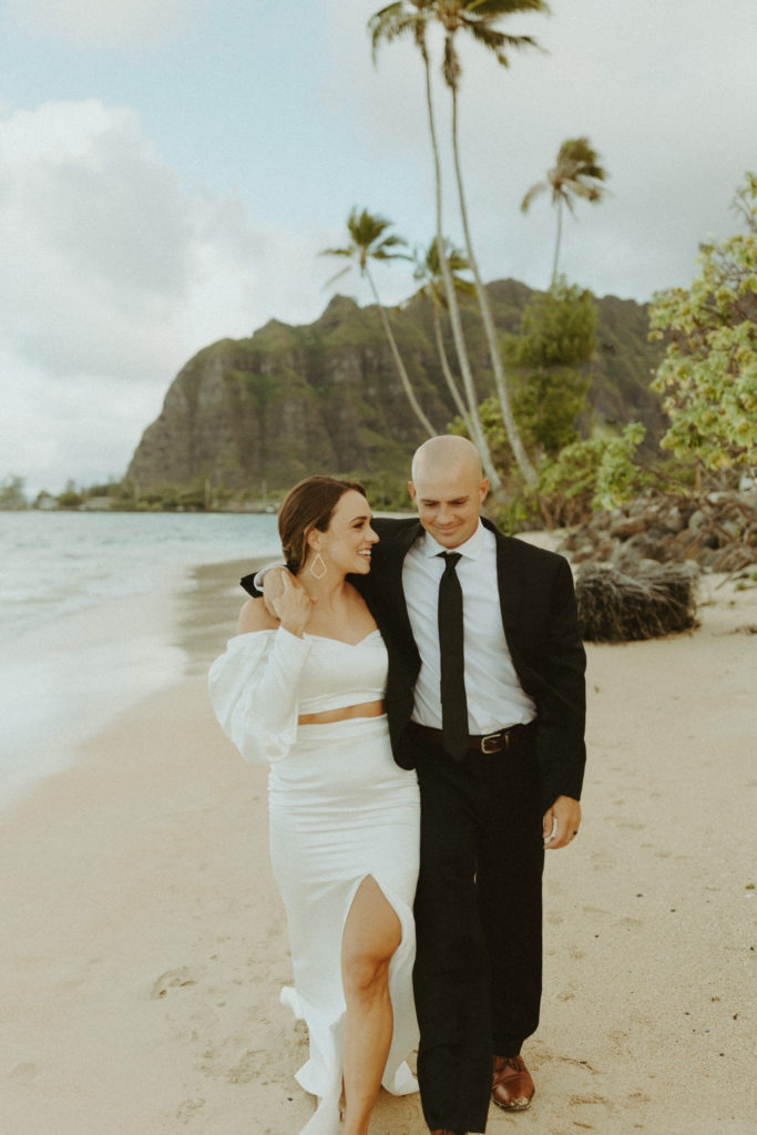 the elopement couple in Hawaii walking down the beach with their arms around each other