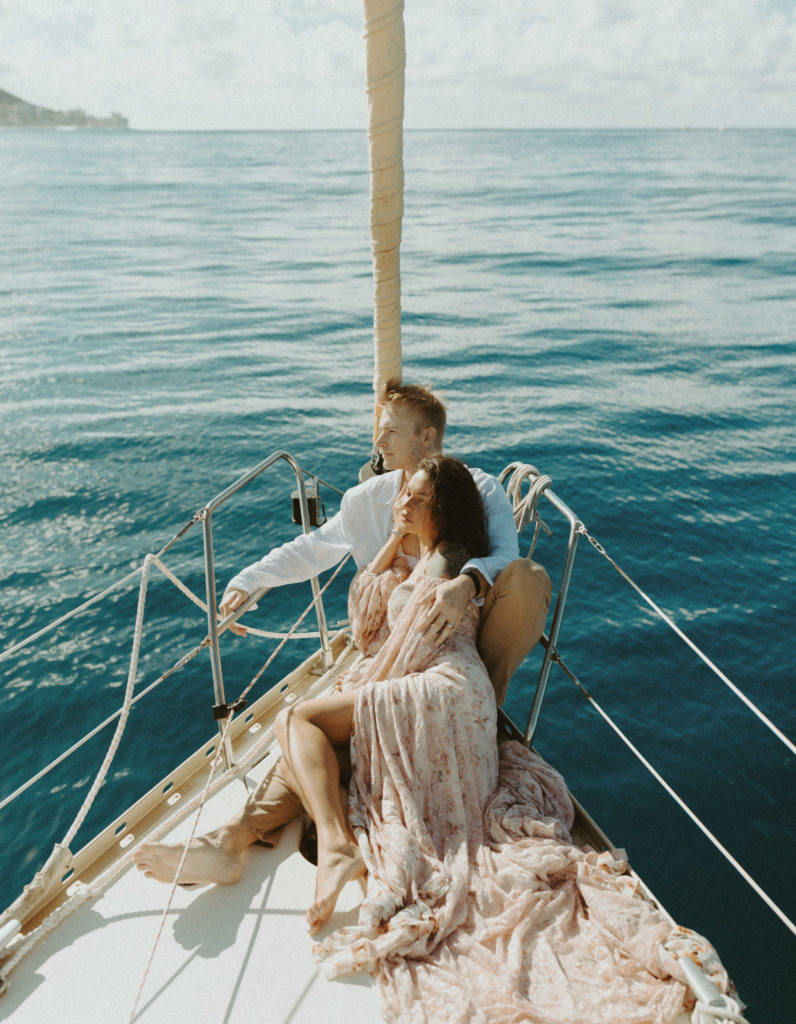 the couple moving their hair out of their eyes on the sailboat