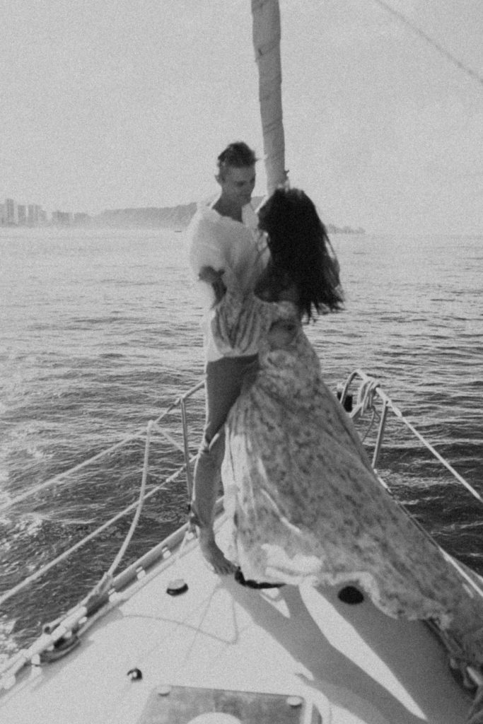 b&w photo of the couple looking at one another on the sailboat