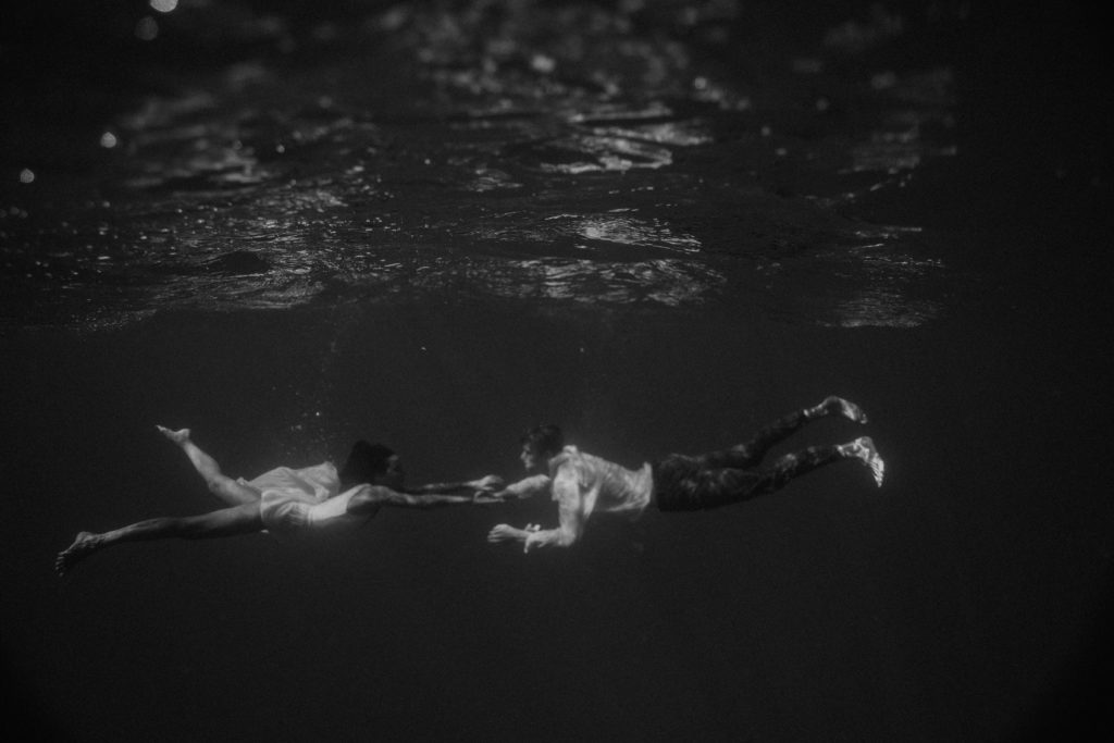 couple touching hands underwater in Hawaii