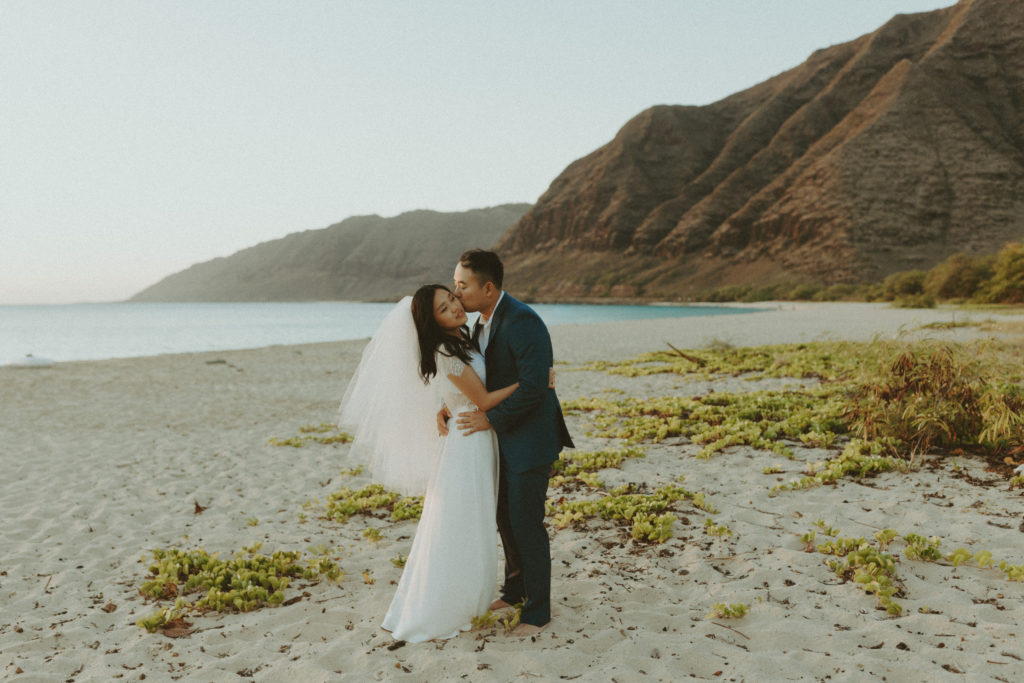 bride and groom posing in hawaii on the beach after their elopement