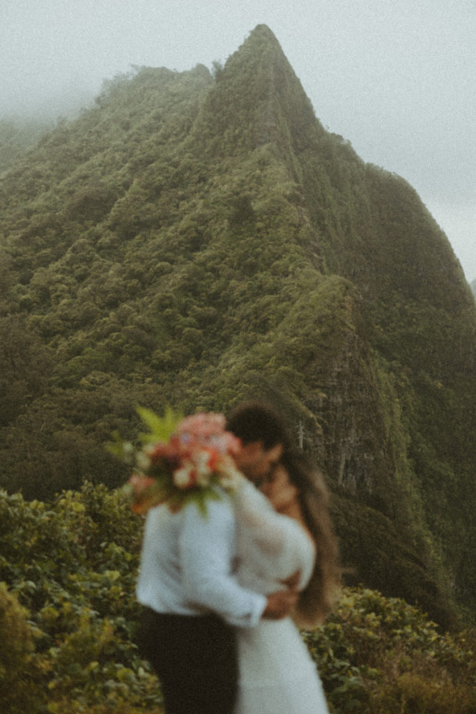 couple posing for wedding photos on a mountain with gorgeous boho wedding flowers
