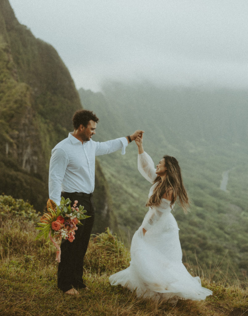 couple posing for wedding photos on a mountain with gorgeous boho wedding flowers