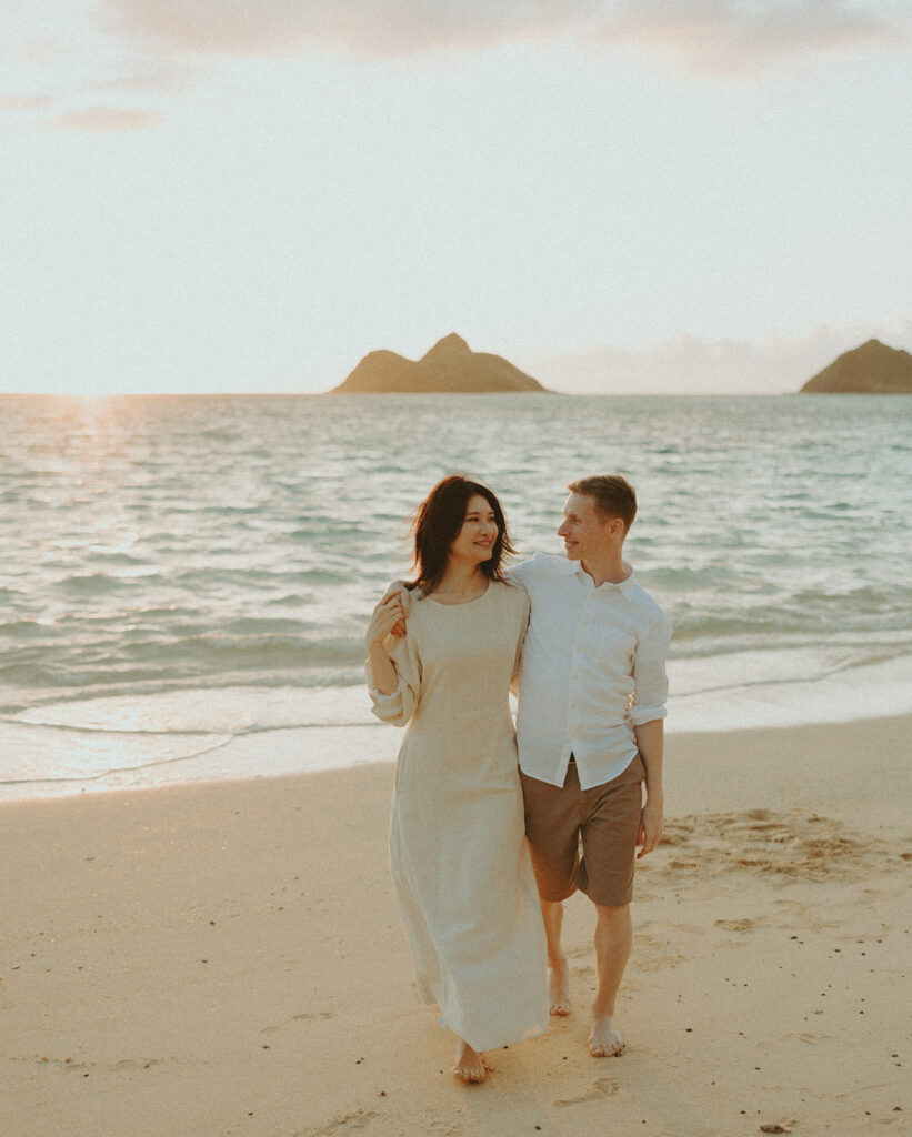 A couples photos on the beach in oahu posing in the sand and playing in the ocean
