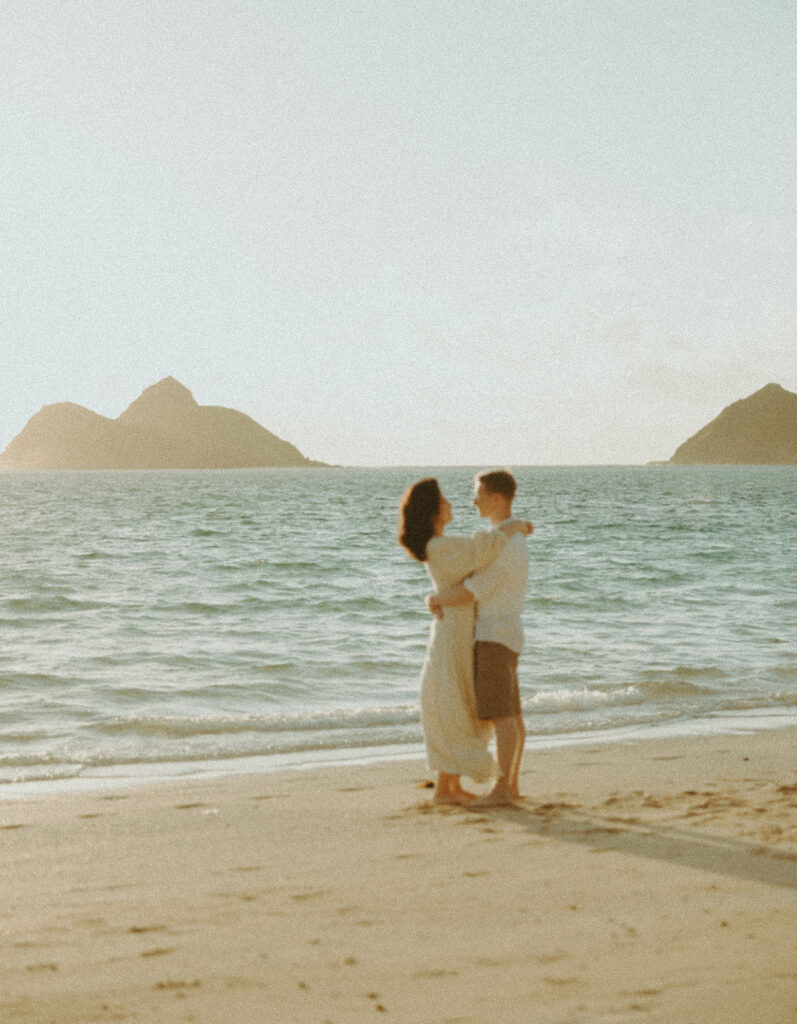 a couple playing in the ocean during golden hour for their mini couples session
