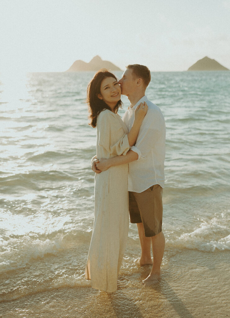 a couple playing in the ocean during golden hour for their mini couples session
